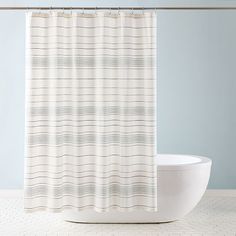 a white shower curtain sitting next to a bath tub