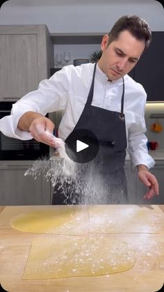 a man in an apron is sprinkling flour on a wooden table