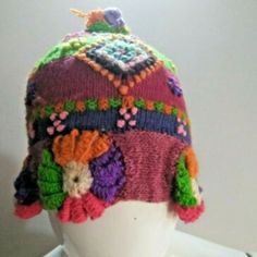 a white mannequin head wearing a multicolored knitted hat with flowers