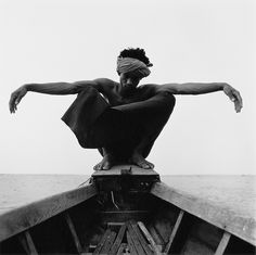 a black and white photo of a man sitting on top of a boat