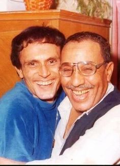 two men are smiling and hugging each other