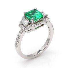 an emerald and diamond ring with two baguets on the shoulders, set in white gold