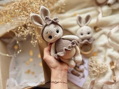 a hand holding a stuffed animal in front of a box with other items on it