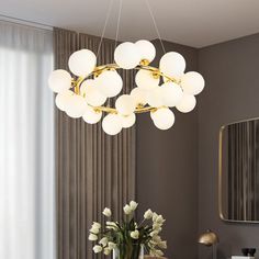 a modern chandelier hanging over a dining room table with flowers in a vase