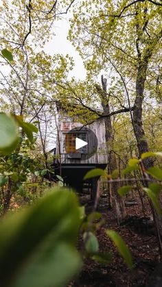 a tree house in the woods surrounded by trees and leaves, with a video screen showing it