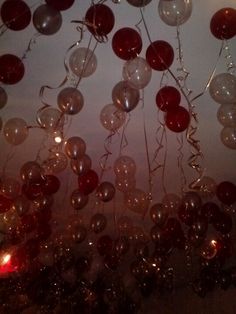 many balloons are floating in the air with lights on them and some candles lit up behind them