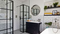 a white and black tiled bathroom with a bathtub, sink, mirror and shower