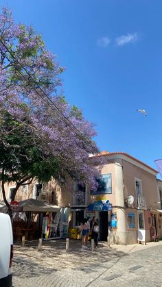 a tree with purple flowers is in front of a building on the side of a road