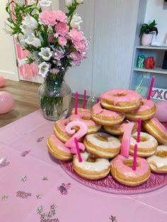 a table topped with donuts covered in pink frosting and sprinkles