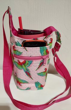 a pink bag with birds on it and a cell phone in the pocket, attached to a lanyard