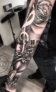 a man's arm with music notes and roses on it