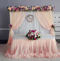 a bed covered in pink and white flowers next to a wall with curtains on it