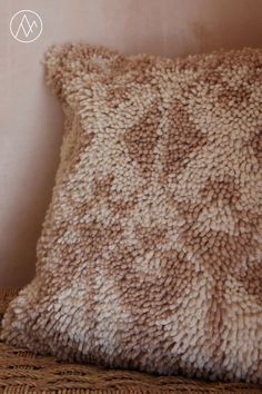 a brown and white pillow sitting on top of a wicker chair next to a wall