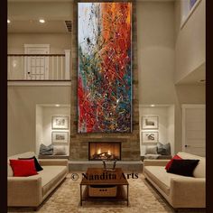 a living room filled with furniture and a large painting on the wall above it's fireplace