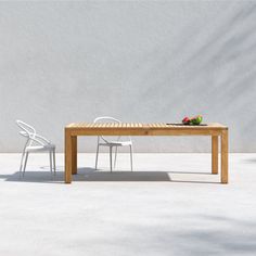 a wooden table with two white chairs and a plate of fruit on top of it