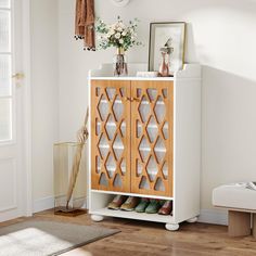 a wooden cabinet with glass doors in a living room next to a rug and flowers