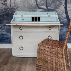 a wicker chair sits in front of a dresser with a glass top on it