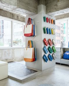 there are many bags hanging on the wall in this room, and one bag is colorful