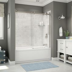 a bathroom with gray walls and white tile on the floor, along with a blue rug