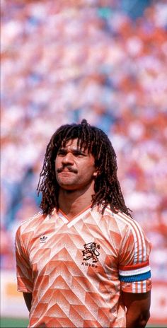 a man with dreadlocks standing in front of a stadium