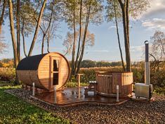 a wooden hot tub sitting on top of a lush green field next to tall trees