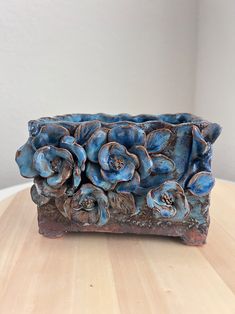 a blue flowered vase sitting on top of a wooden table next to a white wall