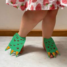 a child's feet wearing green paper shoes with red and white designs on them