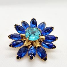 Another Flower Brooch from the vintage blue costume jewelry collection. This one features faceted glass prong set petals in cobalt blue with a large light blue center stone. Cushion or pillow style in that its a raised layered or domed shape. Unmarked but presents the characteristics of well made vintage costume jewelry. Measures approximately 2 inches in diameter. Please don't hesitate to convo if any Qs!  Pet and smoke-free environment. Vintage Blue Diamond Brooch, Blue Flower-shaped Jewelry Brooch, Blue Costumes, Gold Flower-shaped Brooches With Rhinestones, Vintage Gold Flower Shaped Brooch, Gold Flower-shaped Rhinestone Brooches, Pillow Styling, Underwater Photos, Pillows Flowers