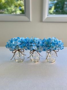 three glass vases with blue flowers in them