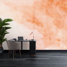 an office with a desk, chair and plant in front of a painted orange wall