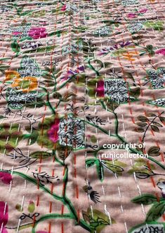 an image of a table cloth with flowers and vines on pink groundcloths that has been embroidered onto it