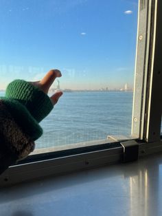 a person's hand sticking out of a window with the ocean in the background