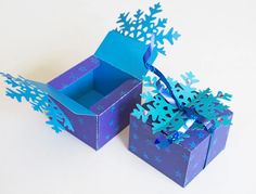 two blue boxes with snowflakes on them sitting side by side, one opened and the other closed