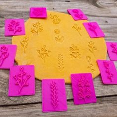 a yellow and pink cookie sheet with flowers cut out of it sitting on a wooden table