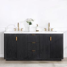 two sinks in front of a black cabinet with gold handles