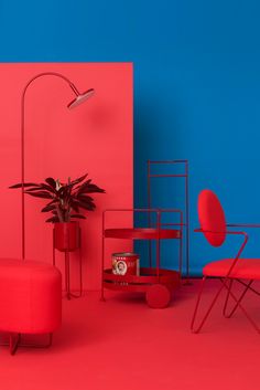 a room with red chairs and a plant in the corner next to a blue wall