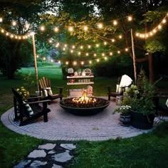 an outdoor fire pit surrounded by chairs and lights