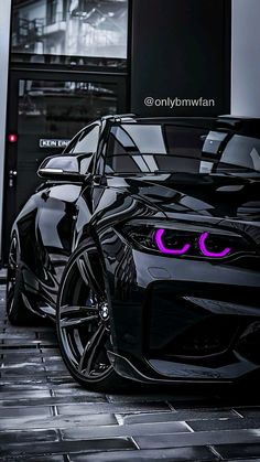 the front end of a black sports car with pink eyes on it's side