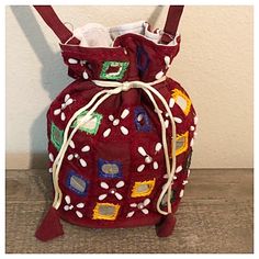 a red bag with white and blue designs on the front is sitting against a wall