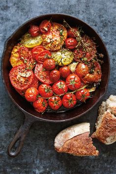 a pan filled with tomatoes and bread on top of a table