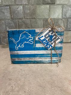 a detroit lions wooden block with the detroit lions logo on it, tied to a rope