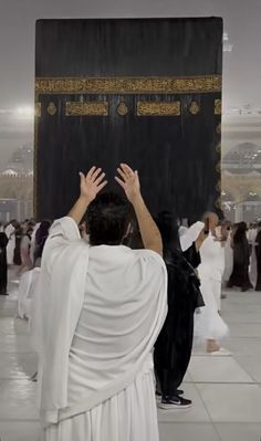 a group of people standing in front of a black and gold ka'bah