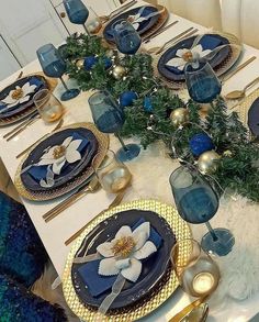 the table is set with blue and gold plates, napkins, and silverware