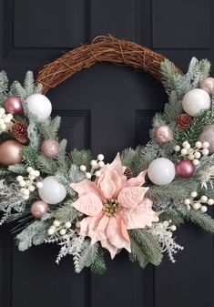 a christmas wreath with poinsettis, pine cones and other decorations hanging on a door