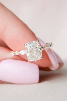 a woman's hand holding an engagement ring with a white diamond in the middle