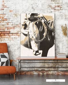 an orange chair sitting in front of a painting on the wall next to a brick wall