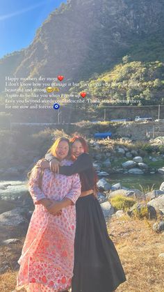 two women standing next to each other in front of a mountain with a quote on it