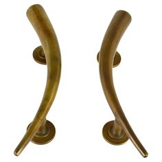 two brass colored metal handles on white background