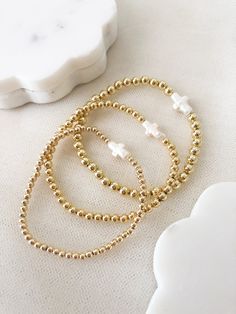 ☞ Features  ✤ Dainty, and beautiful cross shaped freshwater pearl on a 14k gold layered beaded bracelets. ✤ Choose your bead size and adjust it to your wrist in the drop- box.  ✤ The beads are made of a thick and sturdy 18k gold plated material.  ✤ Gently Handmade and Polished  ☞ Shipping ✤ Packages are sent out in 1-2 days after orders are placed from Monday through Saturday. ✤ All orders come ready to gift in our beautiful packaging. ✤ I have tried to design our packaging to be as sustainable Dainty Beaded Gold Bracelet, Dainty Gold Beaded Bracelet, Dainty Beaded Bracelet With Gold Beads As A Gift, Dainty Hand-strung Stretch Bracelet, Delicate Beaded 14k Gold-filled Bracelets, Dainty Gold Beaded Bracelets With Tiny Beads, Gold Stretch Bracelet With Tiny Beads For Gift, Dainty Beaded Charm Bracelet With Round Beads, Dainty Gold Bead Bracelets For Gifts