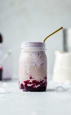 a mason jar filled with whipped cream and blueberry sauce, topped with a gold spoon